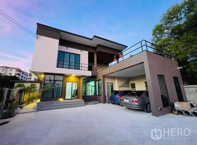 Detached House for sale in Sai Mai, Bangkok - Daytime view of the contemporary house with a wide driveway and rooftop terrace above the carport.