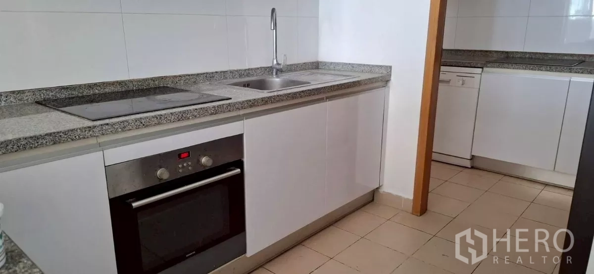 Condominium for rent in Khlong Toei, Bangkok - Modern galley kitchen with cooktop, sink and dishwasher.
