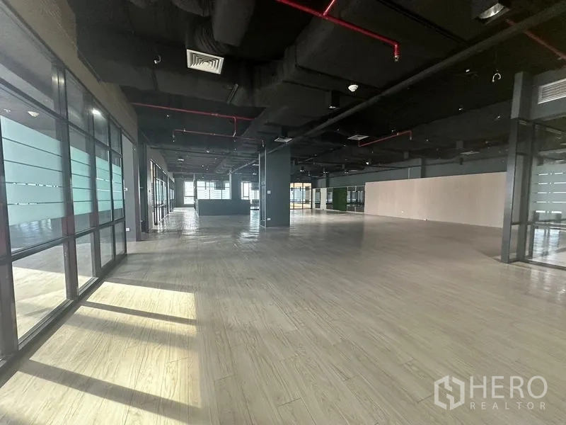 办公空间 出租在Bang Rak, Bangkok - 宽阔开放办公楼层，多排窗户让日光洒满木地板。