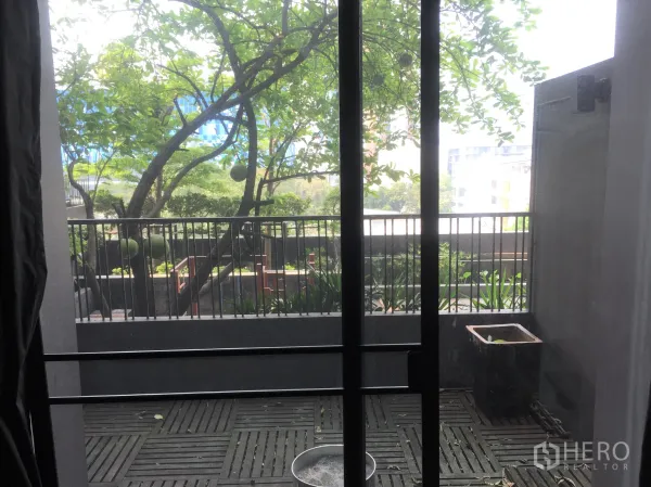公寓 出租或出售在Watthana, Bangkok - 带木质地板的私家阳台，俯瞰绿意庭院与部分城市景观。