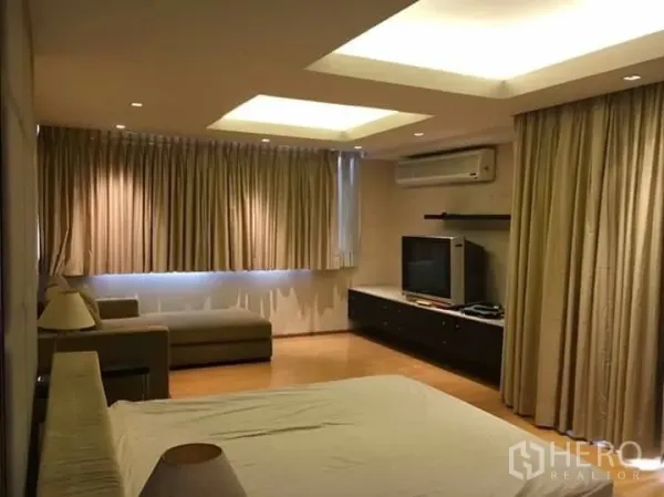 公寓 出租在Watthana, Bangkok - 主卧空间大，带电视柜与沙发，落地窗帘、木地板与嵌灯吊顶。