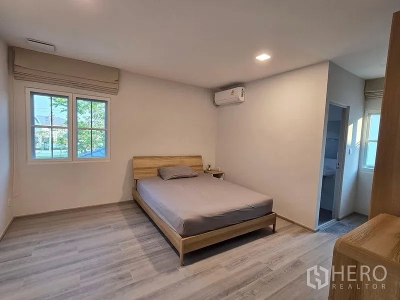 Detached House for rent in Bang Phli, Samut Prakan - Minimalist bedroom with wooden bed, window and access to an ensuite bathroom.