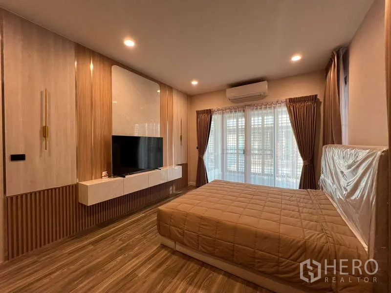 Detached House for rent in Bang Kapi, Bangkok - Master bedroom from another angle showing king bed, TV wall and air conditioner.