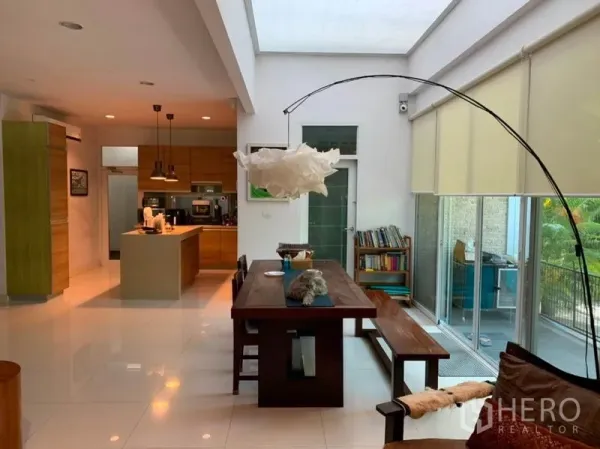 Detached House for sale in Suan Luang, Bangkok - Bright open-plan dining and kitchen with skylight, long wooden table, island and floor-to-ceiling windows.