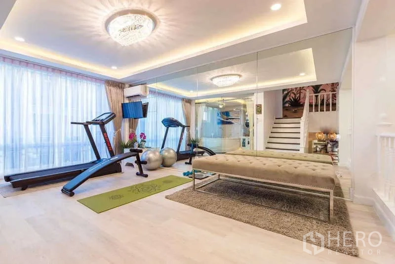 Townhouse for rent in Lat Phrao, Bangkok - Home gym room with treadmills, mirrored wall, large windows and recessed ceiling lights.