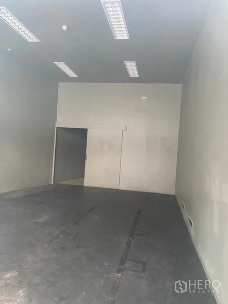 Retail Space for rent in Khlong Toei, Bangkok - Empty retail unit with high ceiling, fluorescent lighting, and concrete floor.