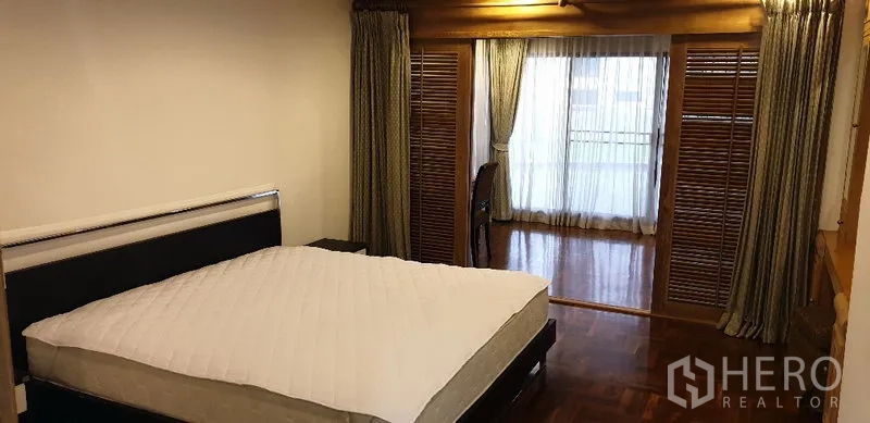 อพาร์ทเมนท์ ให้เช่าในWatthana, Bangkok - ห้องนอนกว้าง พื้นไม้ขัดเงา ประตูบานเกล็ด มุมโต๊ะทำงาน และทางออกสู่ระเบียงผ่านผ้าม่านโปร่ง