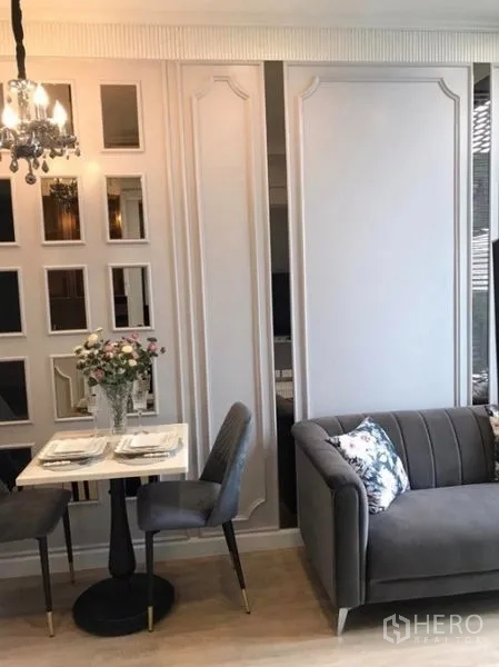 Condominium for rent in Watthana, Bangkok - Dining nook for two beside mirror accent wall and a grey sofa