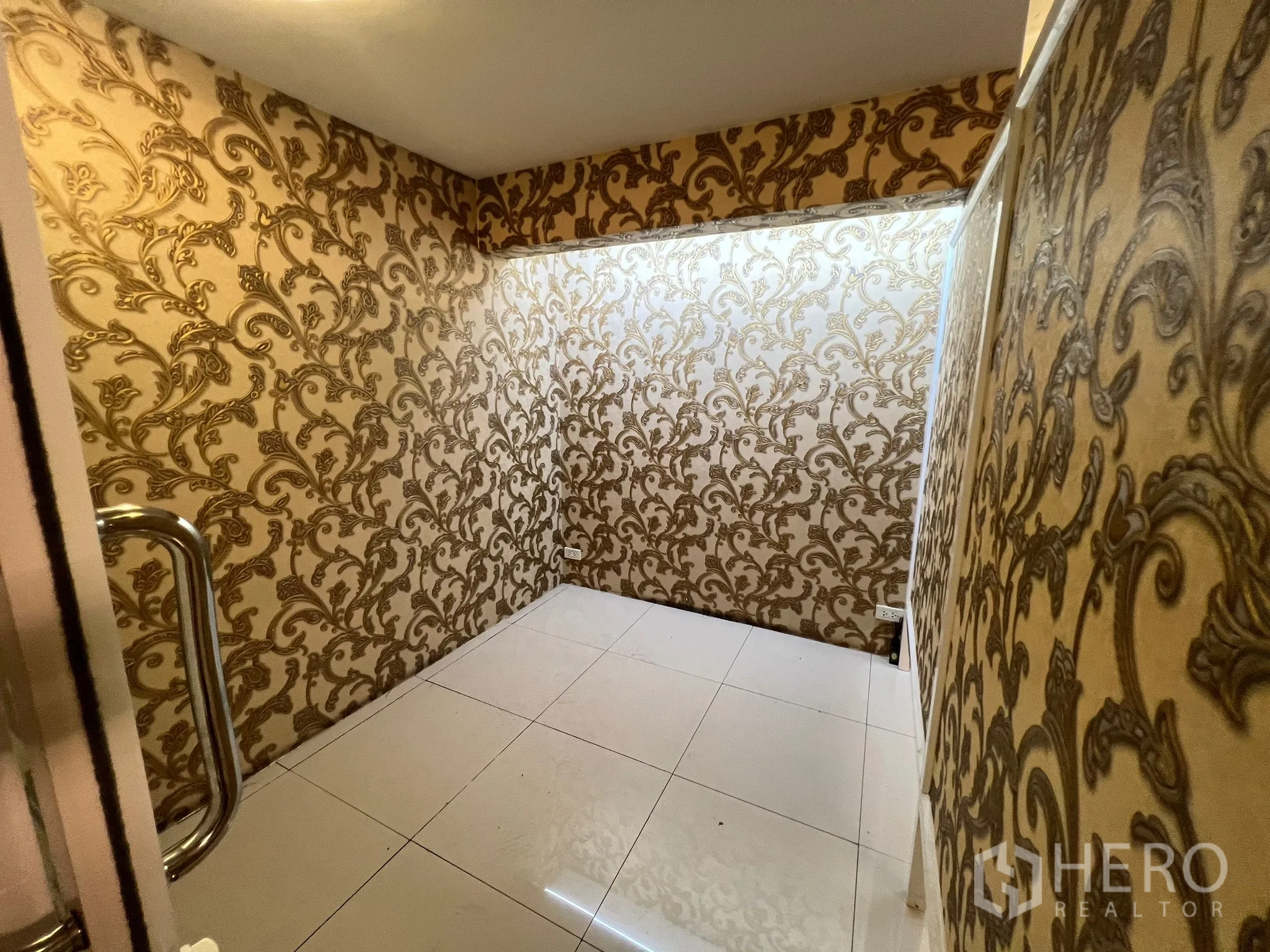 Shophouse for rent in Khlong Toei, Bangkok - Cozy room with gold patterned wallpaper and white tiled floor viewed from the doorway.