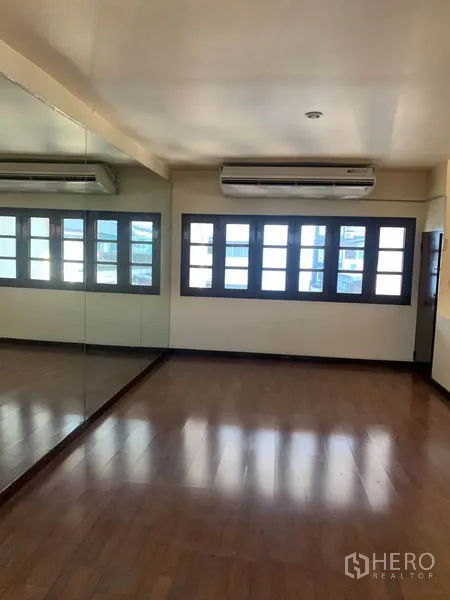 联排别墅 出租或出售在Phra Khanong, Bangkok - 明亮房间，整面镜墙与多格窗户，配壁挂式空调。