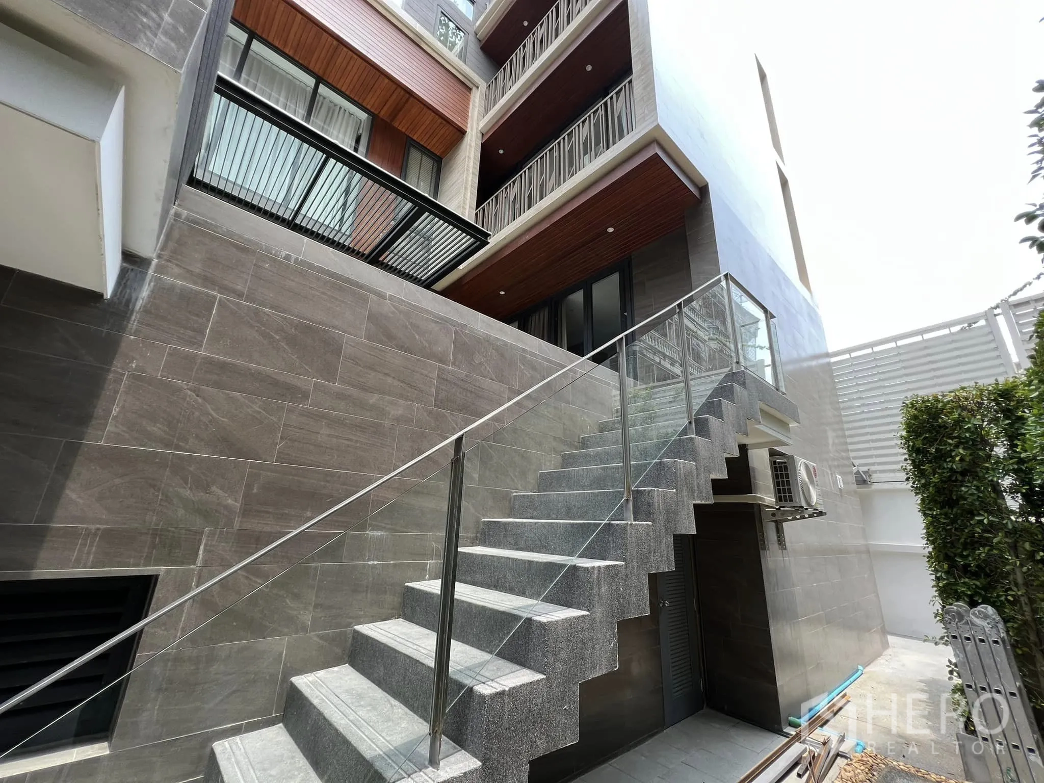 Detached House for rent or sale in Yan Nawa, Bangkok - Exterior side staircase with glass railing and stone cladding.