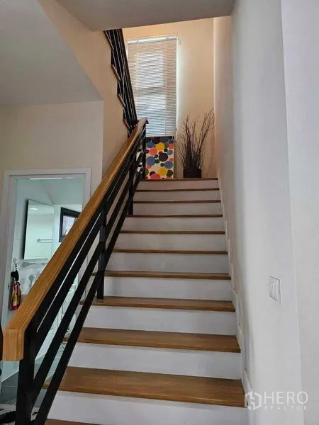Detached House for sale in Khan Na Yao, Bangkok - Staircase with wooden treads and black railing leading to the upper floor.