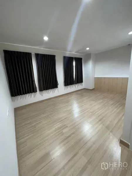 Home Office for rent - Bright office room with laminate flooring and three windows dressed with dark blackout curtains.