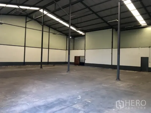 Warehouse for rent in Lam Luk Ka, Pathum Thani - Spacious warehouse interior with high steel truss roof, skylight strips, concrete floor, and tall columns.