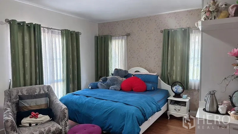 Detached House for rent in Bang Phli, Samut Prakan - Spacious bedroom with blue bedding, multiple windows, and a wallpapered feature wall.