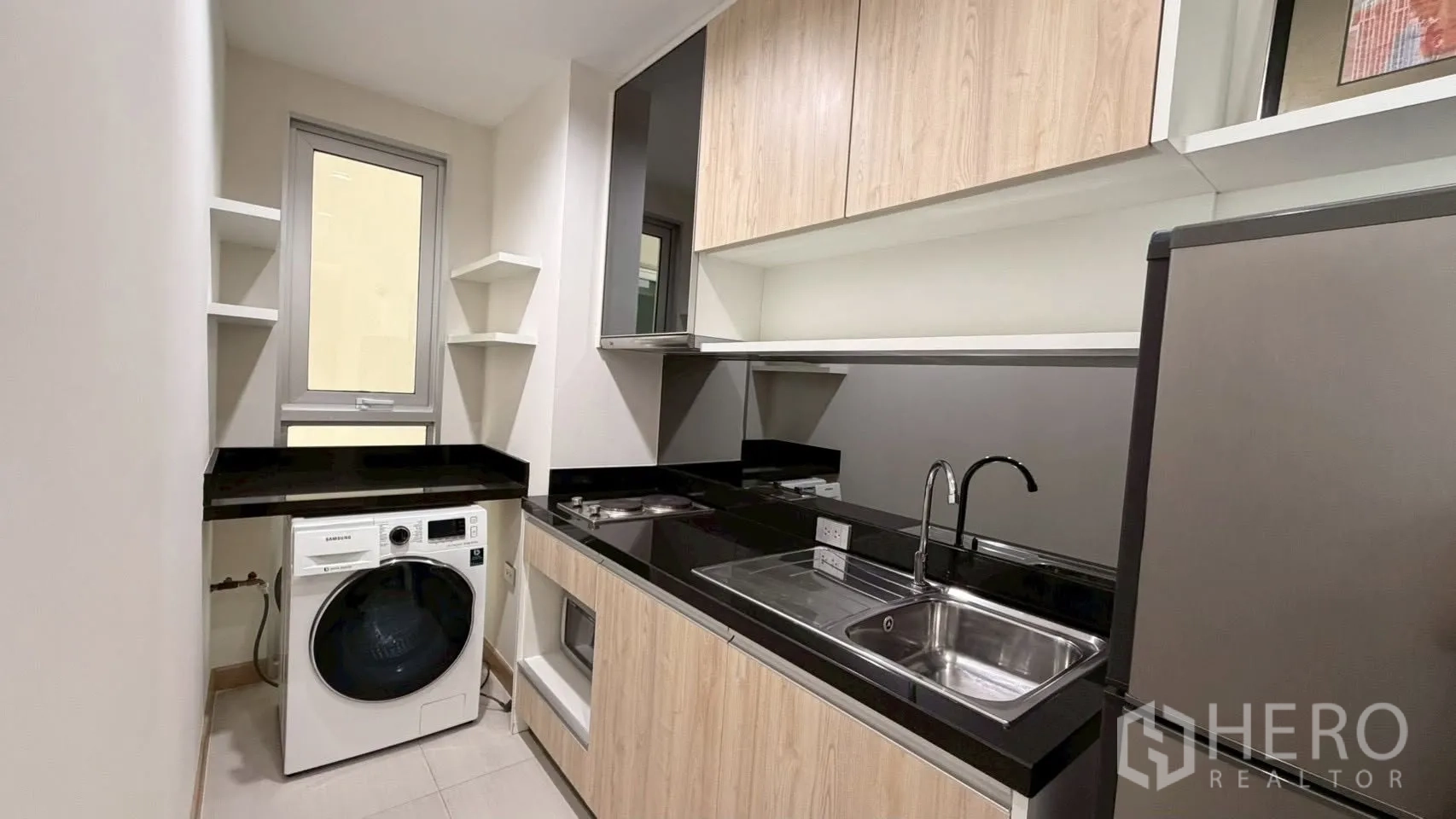 คอนโด for rent or sale in Watthana, Bangkok - ครัวแยกแบบแกลเลย์ เคาน์เตอร์หินสีดำ อ่างล้างจาน เตาไฟฟ้า ตู้เย็น และเครื่องซักผ้า