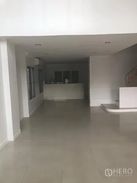 带办公室的家 出租或出售在Watthana, Bangkok - 一层开放式空间，瓷砖地面，白色茶水柜与弧形楼梯。