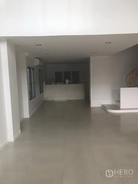 带办公室的家 出租或出售在Watthana, Bangkok - 一层开放式空间，瓷砖地面，白色茶水柜与弧形楼梯。