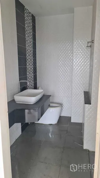 Townhouse for  in Lam Luk Ka, Pathum Thani - Modern bathroom with vessel sink, countertop, toilet and gray floor tiles.
