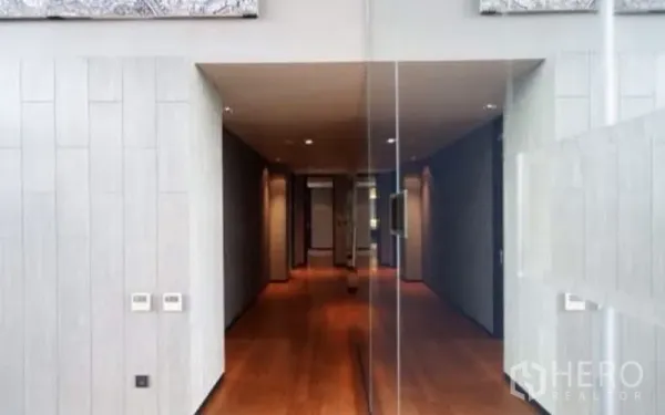Condominium for rent in Sathon, Bangkok - Bright corridor with wooden flooring, recessed lighting and a glass wall leading to the main rooms.