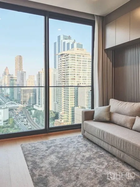公寓 出租在Bang Rak, Bangkok - 沙发靠大型推拉落地窗，无遮挡高楼景观。