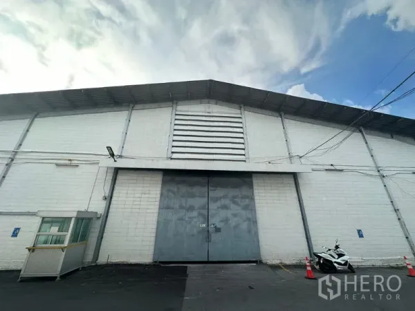 Warehouse for rent in Khlong Toei, Bangkok - Warehouse exterior with large metal double doors, vented facade and a small security booth.