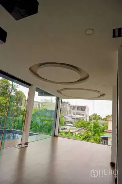 独立式住宅 出售在Lat Phrao, Bangkok - 采光充足的客厅，圆形吊顶与落地玻璃窗，可望绿景。