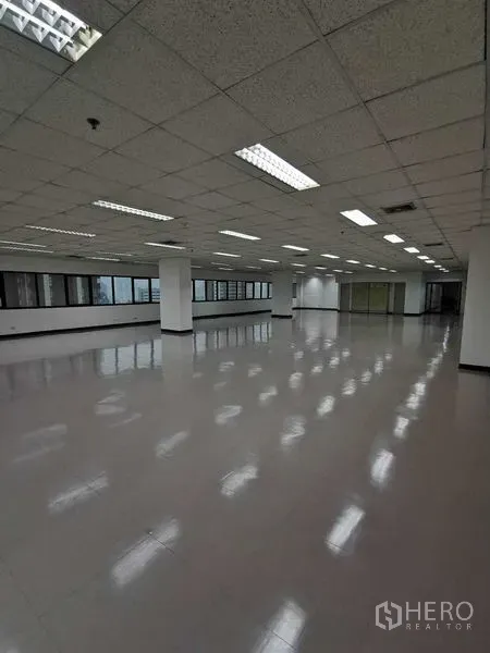 办公空间 出租在Watthana, Bangkok - 宽敞办公楼层，立柱、顶灯与面向城市的窗户。
