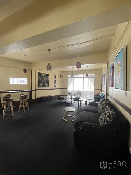 Shophouse for rent in Khlong Toei, Bangkok - Spacious upper-floor lounge in a shophouse with sofa, bar stools, pendant lights and large windows.