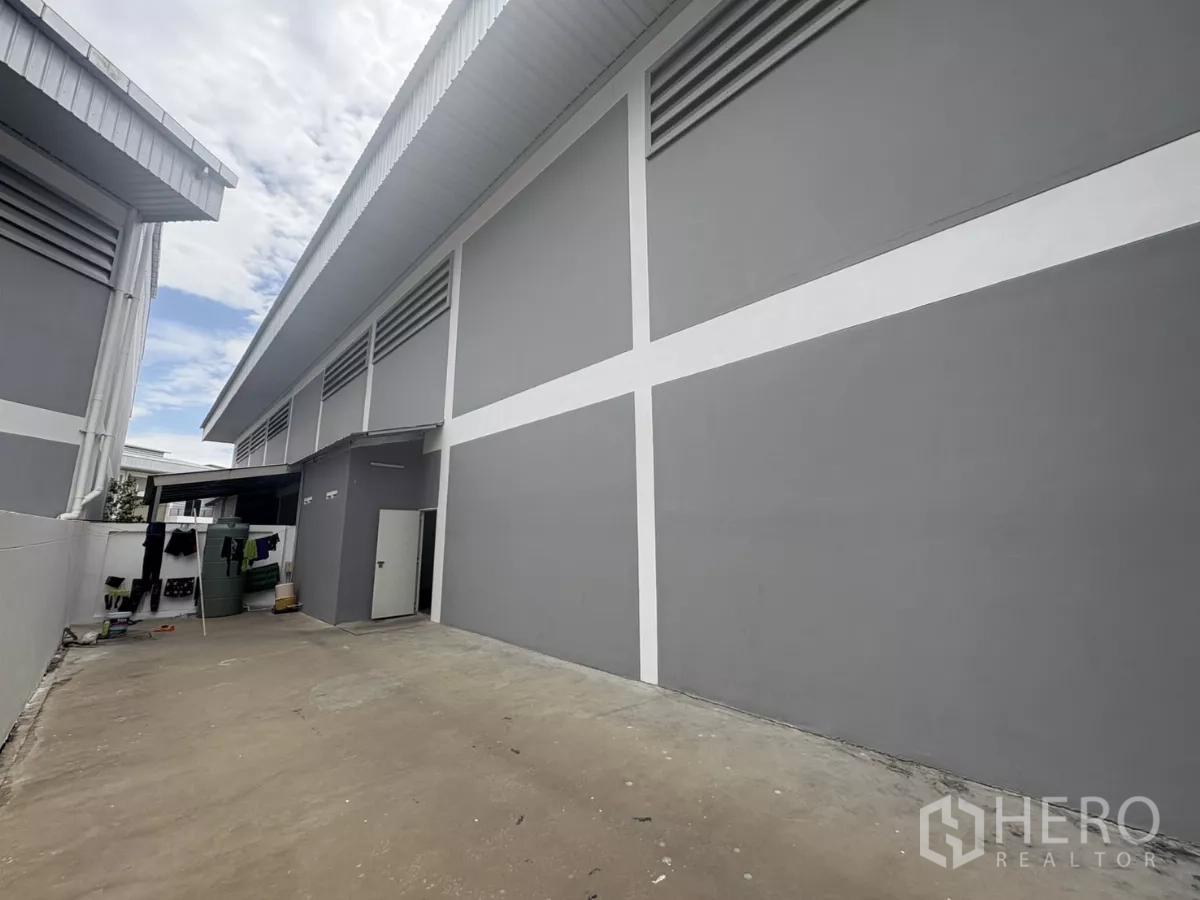Factory for rent in Phra Samut Chedi, Samut Prakan - Side elevation of factory with ventilated panels and utility yard with side door.