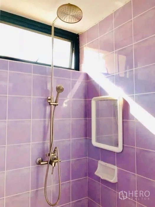 Townhouse for rent in Watthana, Bangkok - Bathroom with purple tiles featuring a rain shower and handheld shower under a high window.