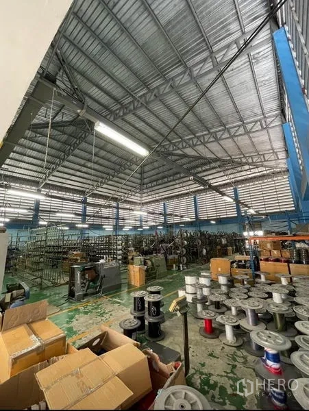Warehouse for sale in Mueang Samut Sakhon, Samut Sakhon - High-clear warehouse bay with steel roof structure and storage racks.