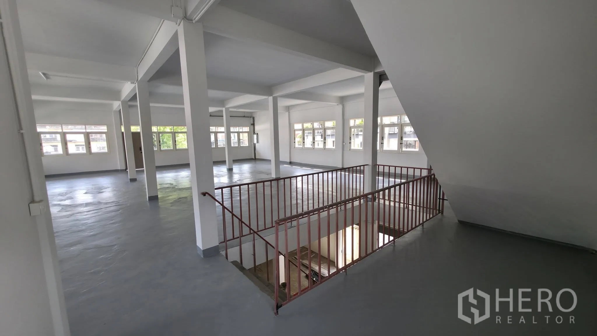 Warehouse for rent in Din Daeng, Bangkok - Open-plan interior with support columns, many windows, and a central stairwell.