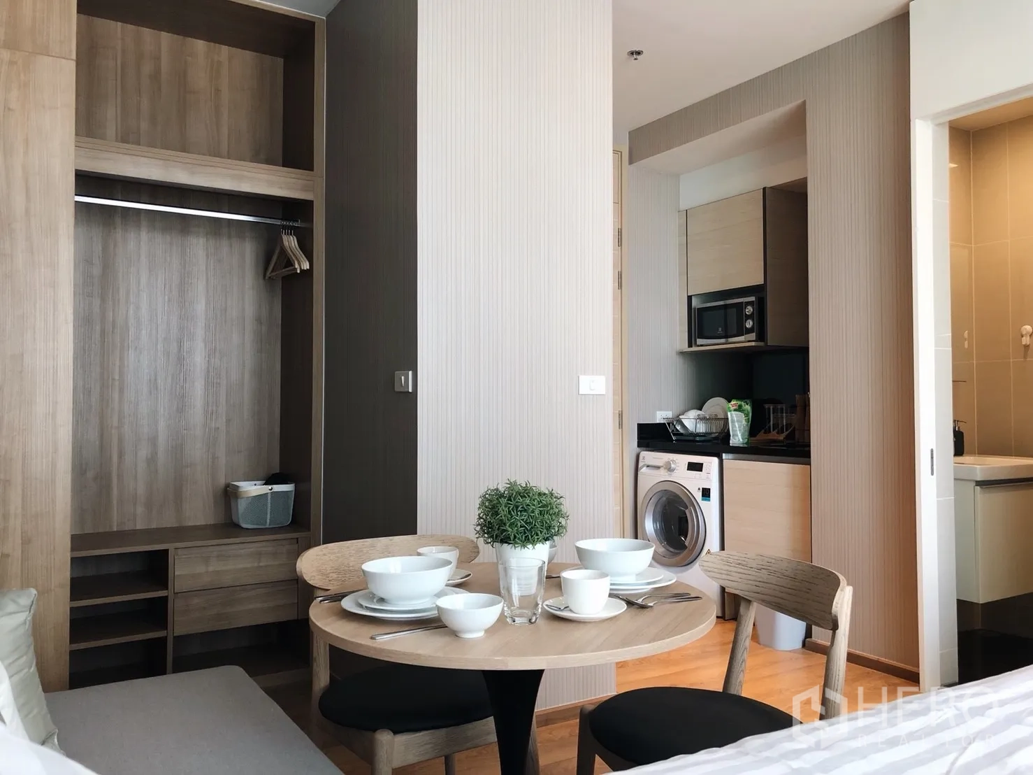 Condominium for rent in Khlong Toei, Bangkok - Compact studio dining area beside open wardrobe and kitchenette with washing machine.