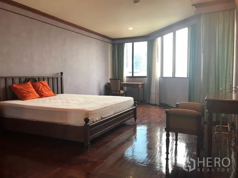 Condominium for rent in Khlong Toei, Bangkok - Spacious master bedroom with large corner windows, work desk and polished wood floors.