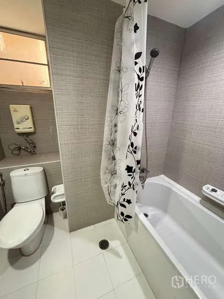 Condominium for rent - Modern bathroom with bathtub, shower curtain and gray textured tiles.