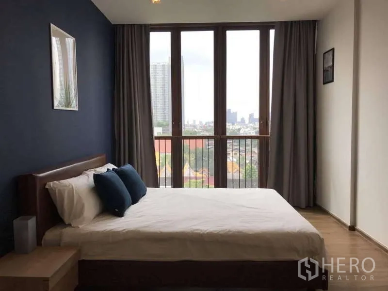 公寓 出租在Watthana, Bangkok - 主卧大窗与城市景，海军蓝背景墙。