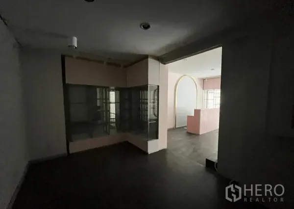 Shophouse for rent in Watthana, Bangkok - Rear room with glass display cabinet and arched opening leading to the front shop area.