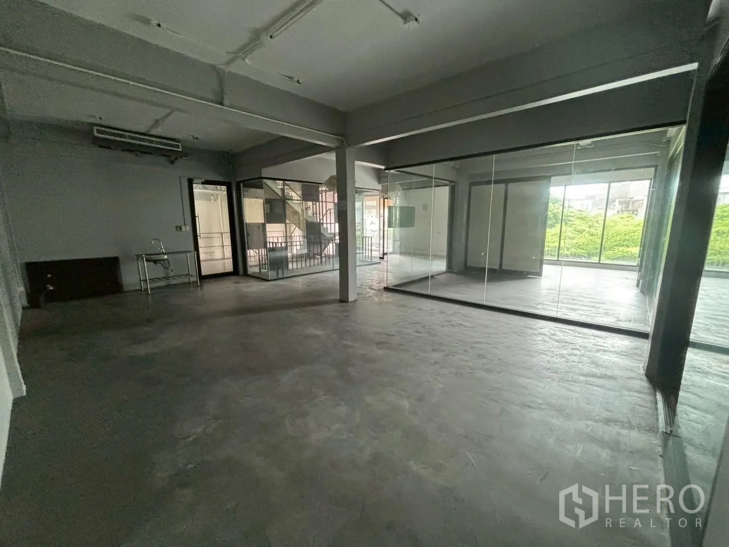 办公空间 出租 - 宽敞的开放式办公室，混凝土地面，玻璃隔间与大窗户可见绿景。
