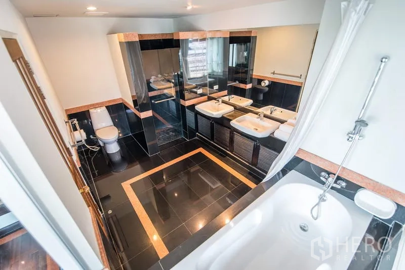 Apartment for rent in Sathon, Bangkok - Spacious bathroom with bathtub, double sinks and a separate shower over glossy black tiles.