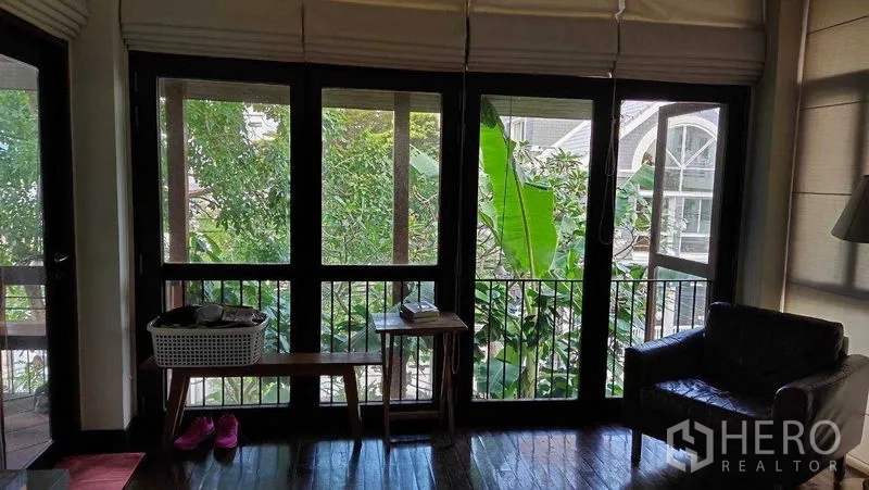 Detached House for sale in Suan Luang, Bangkok - Bedroom corner with full‑height windows showing leafy views and neighboring roofs.