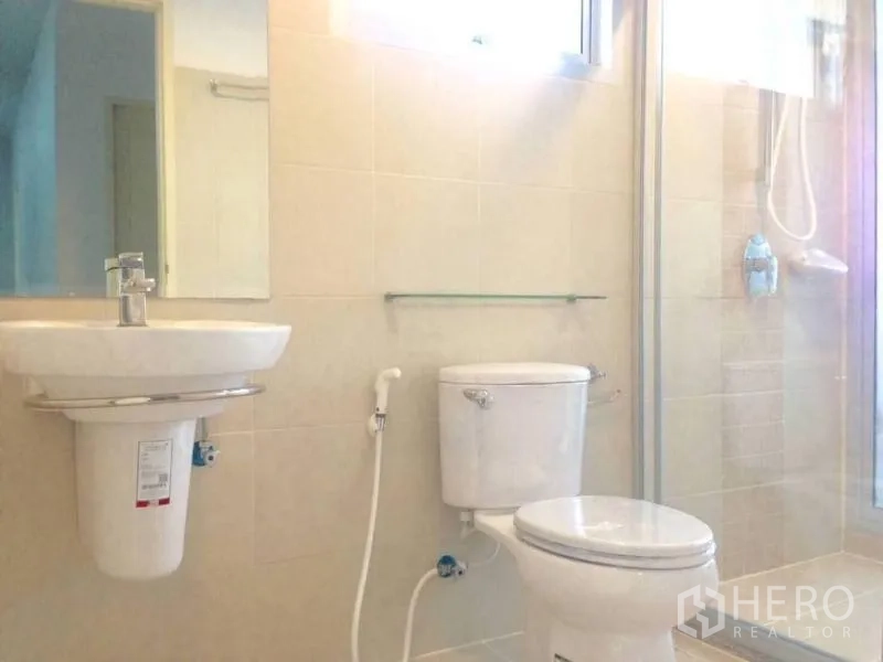 公寓 出租或出售在Huai Khwang, Bangkok - 干净的卫生间，玻璃淋浴间、白色台盆与坐便器。