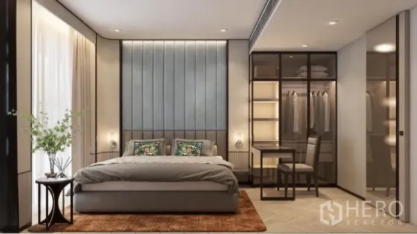 Condominium for rent in Watthana, Bangkok - Modern bedroom with padded headboard, floor‑to‑ceiling window, glass wardrobe with lighting, and a small work desk.