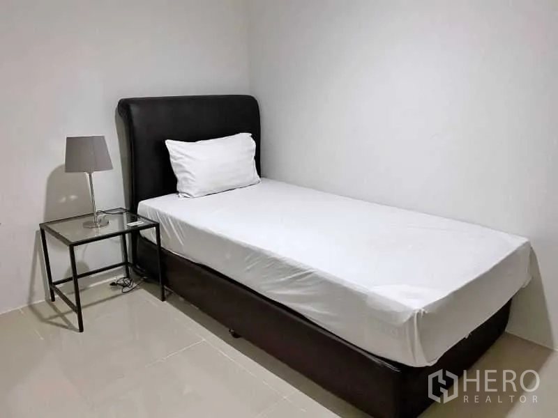 公寓 出租在Khlong Toei, Bangkok - 次卧配单人床、床边桌与台灯，白色墙面。