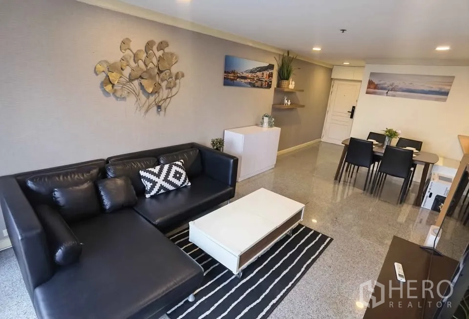 คอนโด for rent in Khlong Toei, Bangkok - โซนนั่งเล่นและทานอาหารแบบเปิดโล่งพร้อมโซฟาหนังตัวแอลและโต๊ะกลาง.