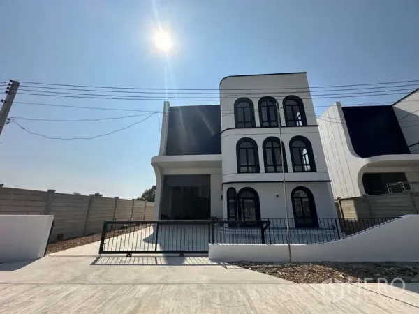 Factory for sale in Lam Luk Ka, Pathum Thani - Modern three-storey factory with arched-window office, gated driveway and perimeter wall under bright sun.