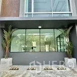 带办公室的家 出租在Wang Thonglang, Bangkok - 一层整面玻璃门面，入口两侧摆放绿植。