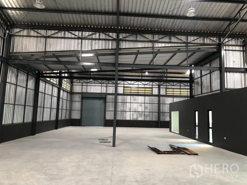 Factory for rent in Bang Yai, Nonthaburi - Wide-span factory hall with a mezzanine platform, ventilation panels and a rear roller door.