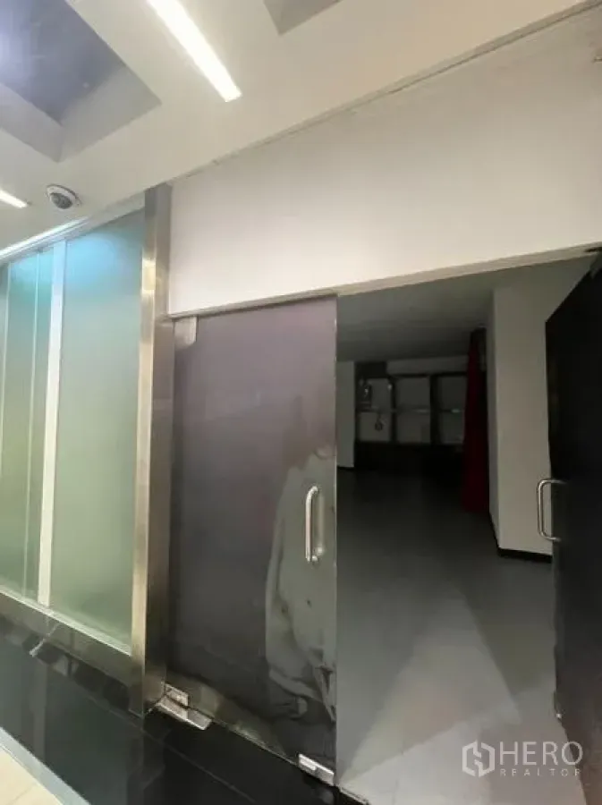 Retail Space for rent in Watthana, Bangkok - Frosted glass double doors leading into a vacant shop unit along an indoor mall corridor.