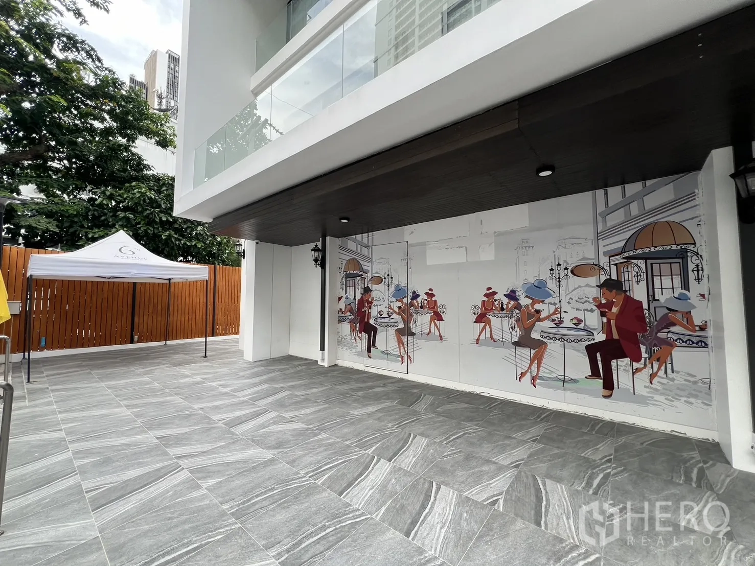 Retail Space for rent - Spacious forecourt in front of the muralled shopfront near landscaped trees.
